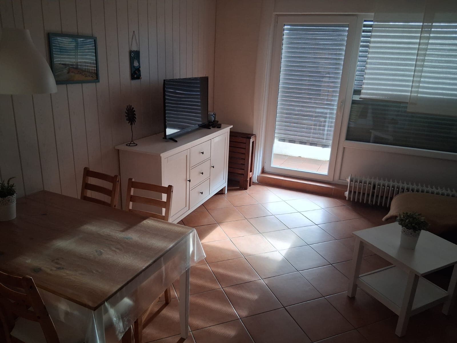 Wohn- und Essbereich mit Sideboard, Fernseher und Balkontür